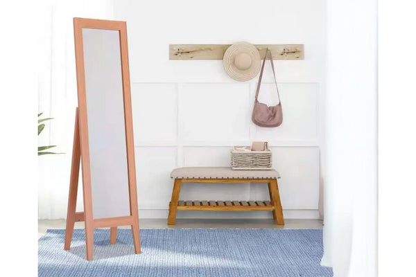 Espejo de piso de madera junto a un banco con un sombrero y un bolso sobre un fondo de pared blanco