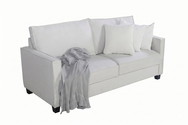 Loveseat beige con cojines blancos y una manta gris sobre un fondo blanco.