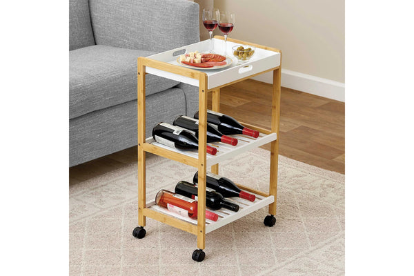 Carrito de servicio de madera con botellas de vino y aperitivos junto a un sofá gris.