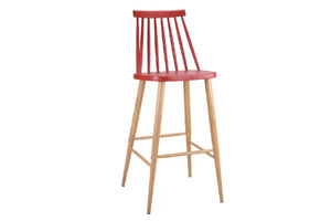 Taburete rojo con patas acabadas en marrón y con reposapiés y respaldar en un fondo blanco. 