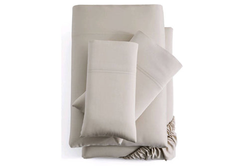 Sábanas y fundas de almohada de color beige dobladas sobre un fondo blanco. 