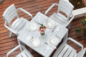 Juego de comedor con mesa color blanco y 4 sillas blancas sobre un piso de madera en el exterior