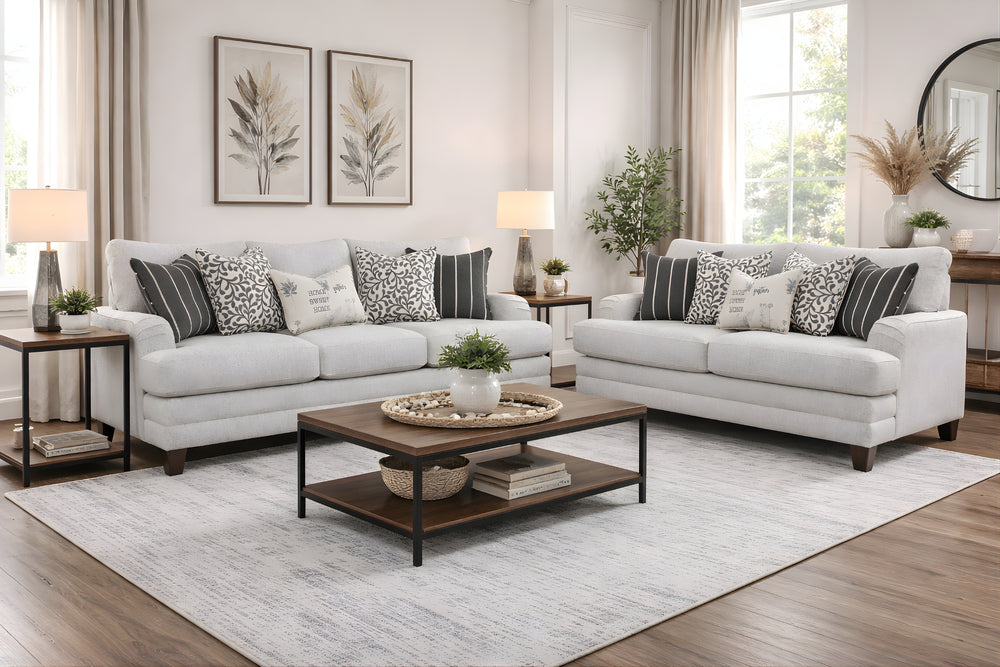 Sofá y loveseat color gris claro con cojines decorativos en un ambiente de sala moderno con elementos decorativos. 