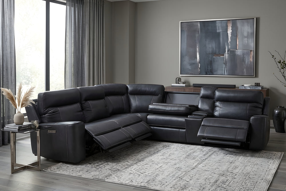 Sofá seccional reclinable negro de apariencia piel, con diseño en L, respaldos acolchados, reposapiés extendidos, consola central, brazos anchos, costuras visibles y controles laterales sobre un fondo blanco.