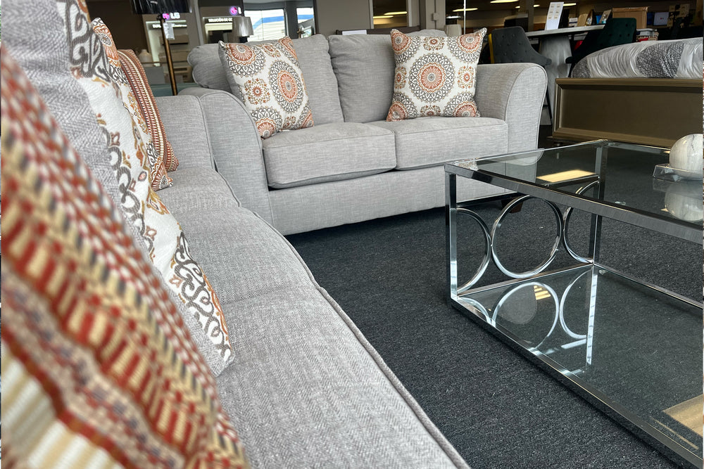 Loveseat de color beige con cojines decorativos sobre un fondo blanco. 