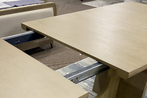 Mesa de comedor rectangular extensible en acabado madera clara, mostrada con mecanismo de extensión abierto y rieles metálicos visibles. La imagen destaca su diseño funcional, superficie amplia y capacidad para acomodar más comensales.