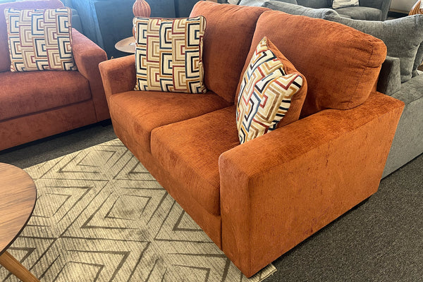 Loveseat de color anaranjado con cojines una sala de exposición