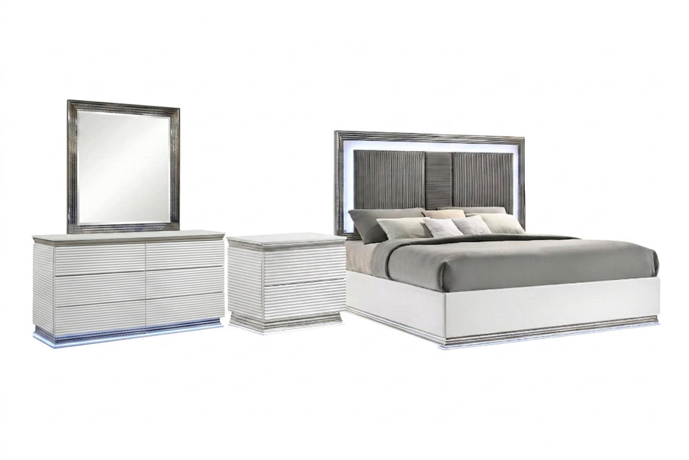 Juego de habitación de color blanco y gris con luces LED integradas que incluye una cama, una mesa de noche y un gavetero con espejo sobre un fondo blanco. 