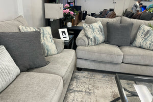 Sofá y loveseat modular gris con cojines estampados en una sala de exposición