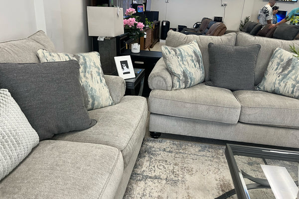 Sofá y loveseat modular gris con cojines estampados en una sala de exposición