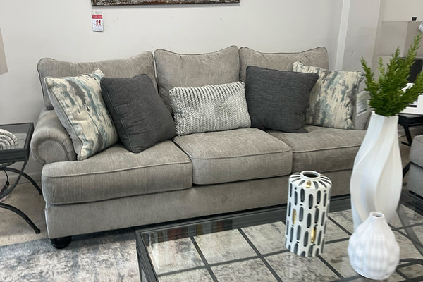 Sofá gris con cojines decorativos en un ambiente de una sala de exposición