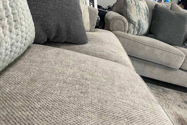 Sofá gris con cojines estampados en una sala de exposición