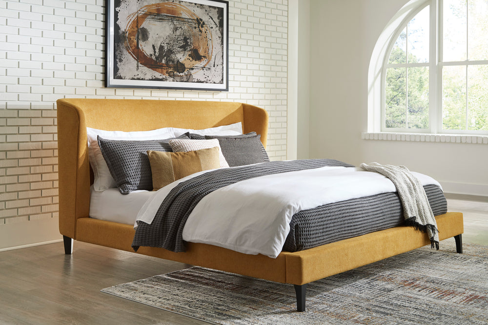 Cama amarilla con mattress y almohadas blancas sobre un fondo blanco.