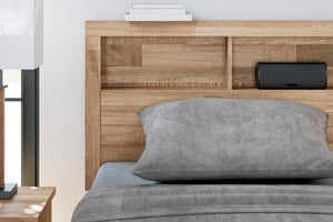 Cama con cabecero de madera y ropa de cama gris en un dormitorio