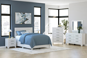 Dormitorio moderno con cama blanca, gavetero con espejo y mesitas de noche sobre una pared azul.