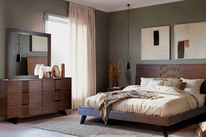 Un dormitorio moderno que cuenta con una estructura de cama de madera oscura con cabecero de listones y ropa de cama en tono beige, un gavetero de madera a juego con espejo y paredes de color verde oliva decoradas con arte abstracto.
