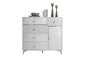 Un chest modern de color blanco brillante y texturizado, con tiradores y patas plateadas, decorada con libros y jarrones decorativos en la parte superior, sobre un fondo blanco liso.