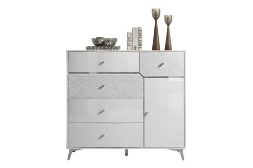 Un chest modern de color blanco brillante y texturizado, con tiradores y patas plateadas, decorada con libros y jarrones decorativos en la parte superior, sobre un fondo blanco liso.