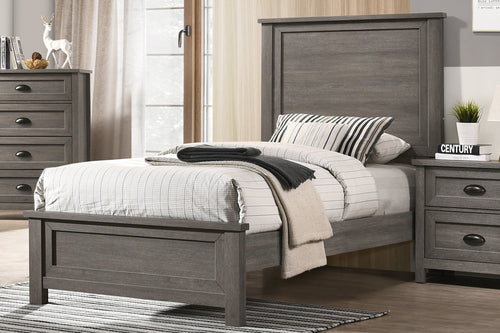 Cama twin hecha de madera color gris en una habitación con una mesa de noche y un chest en el fondo con objetos decorativos. 