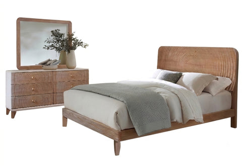 Un conjunto de muebles de dormitorio de estilo moderno de mediados de siglo que incluye una cama con plataforma de madera y cabecero curvo, una cómoda a juego de seis cajones con espejo rectangular y ropa de cama en tonos neutros.