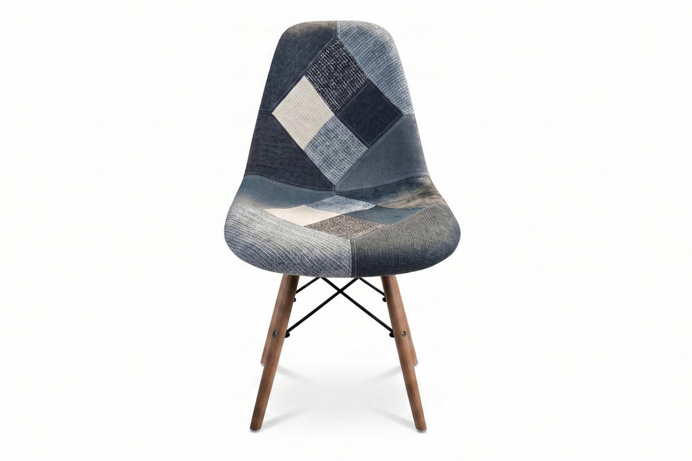 Una moderna silla con asiento y respaldo de tela tipo patchwork en tonos grises, azul marino y blanco, con patas de madera cónicas, sobre un fondo color blanco.