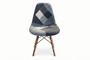 Una moderna silla con asiento y respaldo de tela tipo patchwork en tonos grises, azul marino y blanco, con patas de madera cónicas, sobre un fondo color blanco.