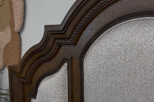 Vista cercana de cabecera hecha de madera marrón oscura con acolchado blanco. 