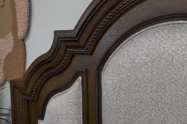 Vista cercana de cabecera hecha de madera marrón oscura con acolchado blanco. 