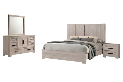 Un conjunto de muebles de dormitorio con acabado en madera gris claro, que incluye una cama con ropa de cama gris, una mesita de noche a juego y una cómoda con espejo, mostrado sobre un fondo blanco liso.