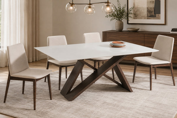 Una escena de comedor moderno que muestra una mesa de comedor rectangular blanca con una base en forma de X de madera oscura, rodeada de cuatro sillas de comedor tapizadas en tonos beige y marrón, dispuestas sobre una alfombra clara en una habitación bien iluminada.