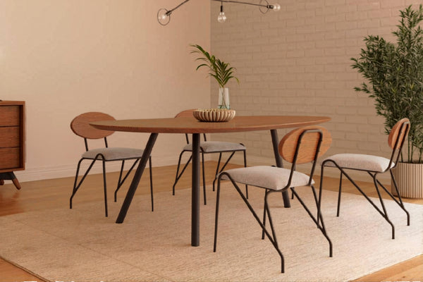 Juego de comedor moderno con mesa rectangular de madera de bordes redondeados y cuatro sillas con respaldo de madera, asientos tapizados en gris claro y estructura metálica negra. Ambientado en un espacio contemporáneo con decoración minimalista y tonos cálidos.