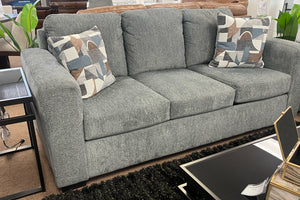 Sofá gris con cojines estampados en un ambiente de sala de estar.