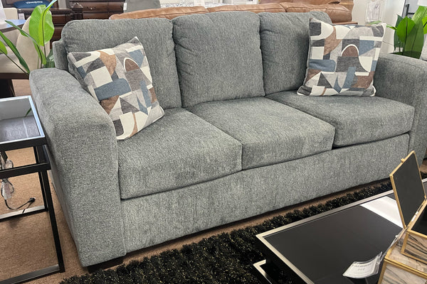 Sofá gris con cojines estampados en un ambiente de sala de estar.