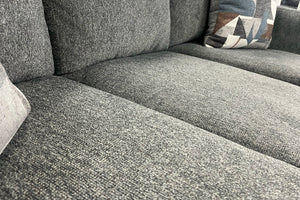 Sofá gris texturizado con un cojín estampado.