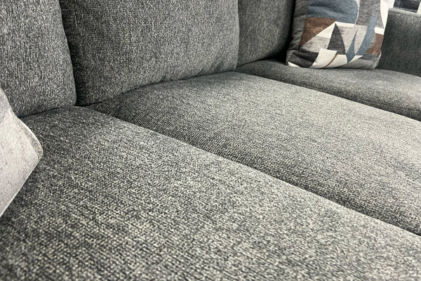 Sofá gris texturizado con un cojín estampado.
