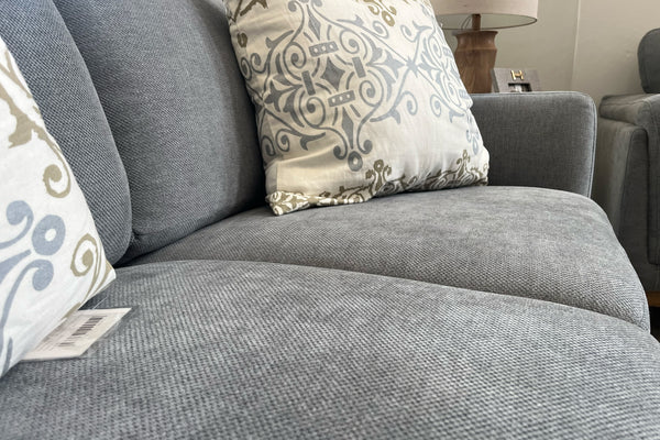 Loveseat gris con cojines estampados en un ambiente de una sala de exposición
