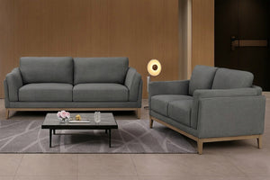 Conjunto de sofá y loveseat grises con mesa de centro en un salón de estilo moderno.