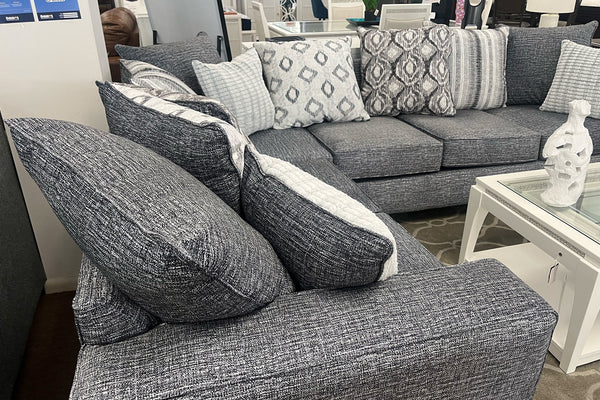Seccional gris con cojines estampados en un ambiente de habitación.