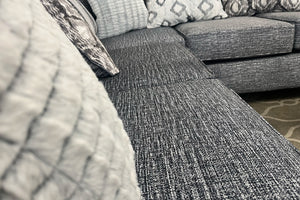 Sofá seccional gris texturizado con cojines estampados.