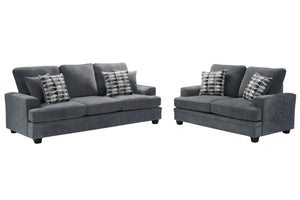Conjunto de sofá y loveseats grises con cojines estampados sobre fondo blanco.