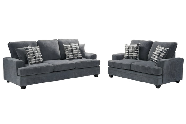 Conjunto de sofá y loveseats grises con cojines estampados sobre fondo blanco.
