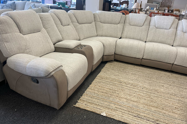 Sofá modular beige con asientos reclinables sobre un suelo alfombrado en una sala de exposición 
