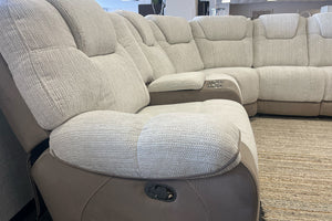 Sofá seccional beige con sillón reclinable en una sala de exposición.