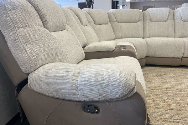 Sofá seccional beige con sillón reclinable en una sala de exposición.