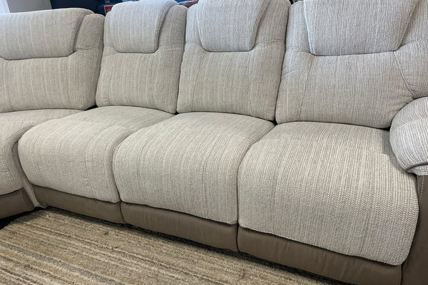 Sofá seccional beige sobre un suelo alfombrado en una sala de exposición.