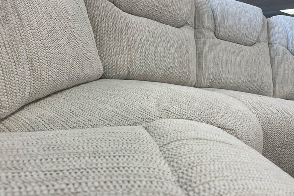 Seccional de tela beige con estampado texturizado en una sala de exposición.