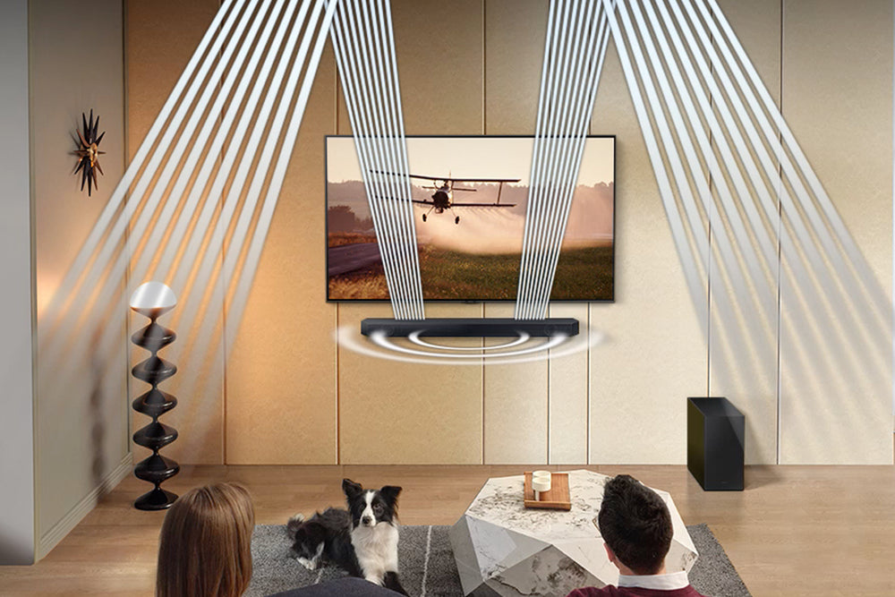 Barra de sonido negra con subwoofer y control remoto sobre fondo blanco. 