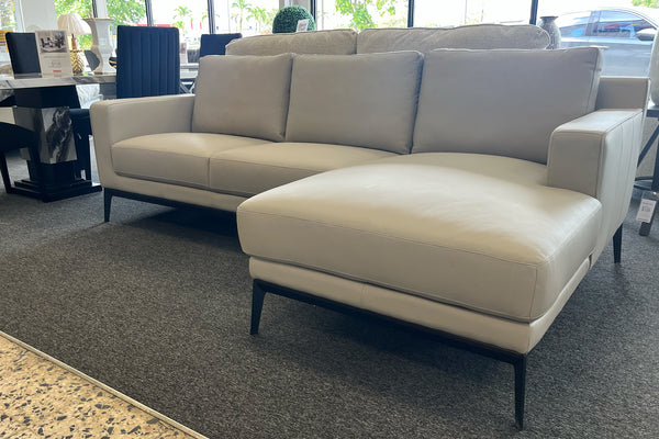 Sofá seccional beige con chaise longue en un entorno de exposición.