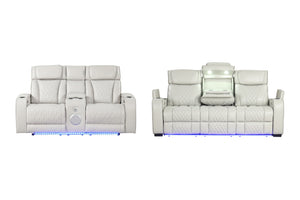 Sofá reclinable de cuero blanco para sala de cine, mostrado de frente y de espaldas sobre un fondo blanco, que cuenta con iluminación LED azul en la base y una consola central con altavoz y compartimento de almacenamiento iluminado.