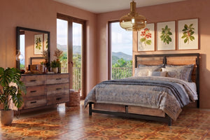 Juego de Habitación moderno con cama de madera y estructura metálica negra, ropa de cama en tonos beige y gris con patrones decorativos, gavetero de madera rústica, lámpara colgante de vidrio ámbar y grandes ventanas con vista a un paisaje tropical.
